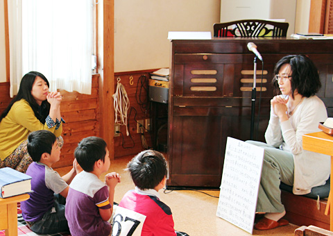 教会学校のスタッフからお祈りの仕方を学ぶ子供たち